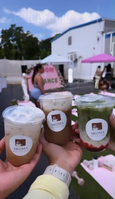 Three iced Aroma Café drinks held up at an outdoor event